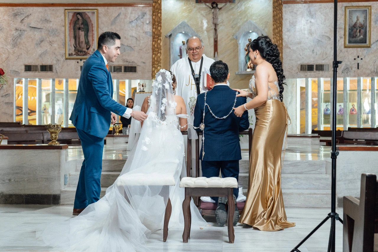 Los novios reciben el lazo en el altar, acompañados por sus padrinos