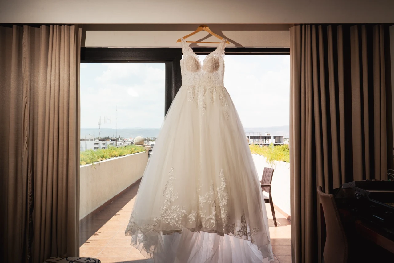 El vestido de novia espera colgado frente a la luz de la ventana