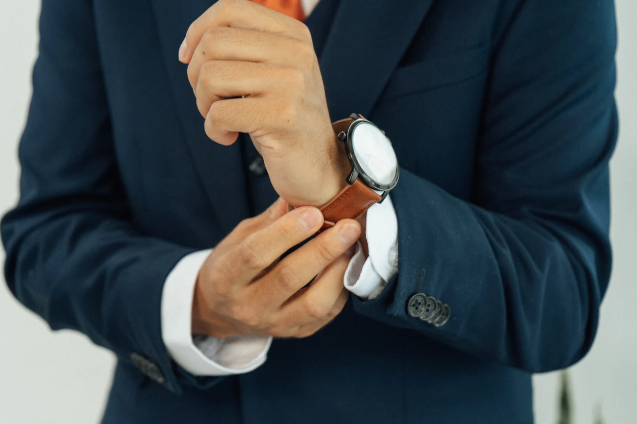 Detalle de las manos del novio ajustando la correa de su reloj