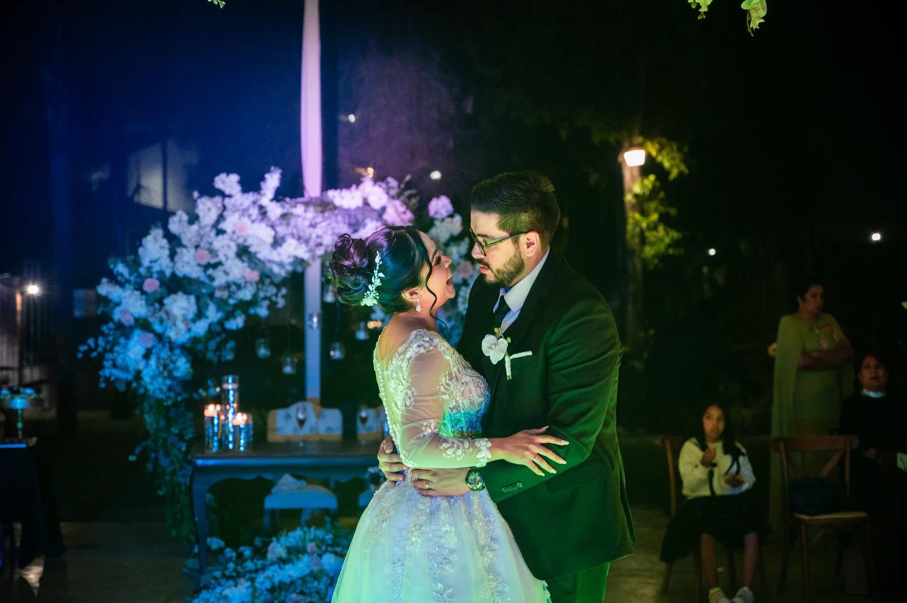 Los novios bailan abrazados bajo las luces de la recepción